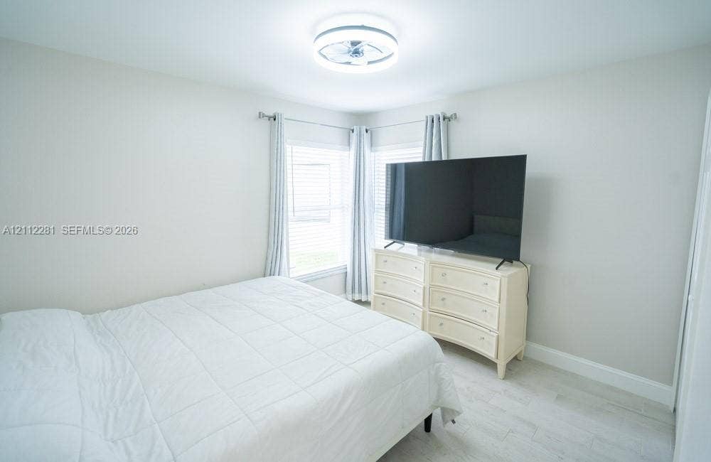 2461 Winfield, Kissimmee, FL 34743 Neutral interior room featuring light-toned wood-finish flooring, dual windows with wall-mounted curtain rods, and a circular LED flush-mount ceiling light