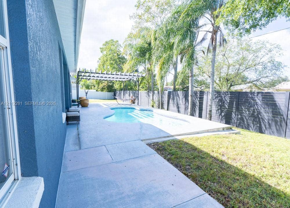 2461 Winfield, Kissimmee, FL 34743 Backyard featuring an in-ground pool, concrete patio, pergola, and horizontal-slat perimeter fencing