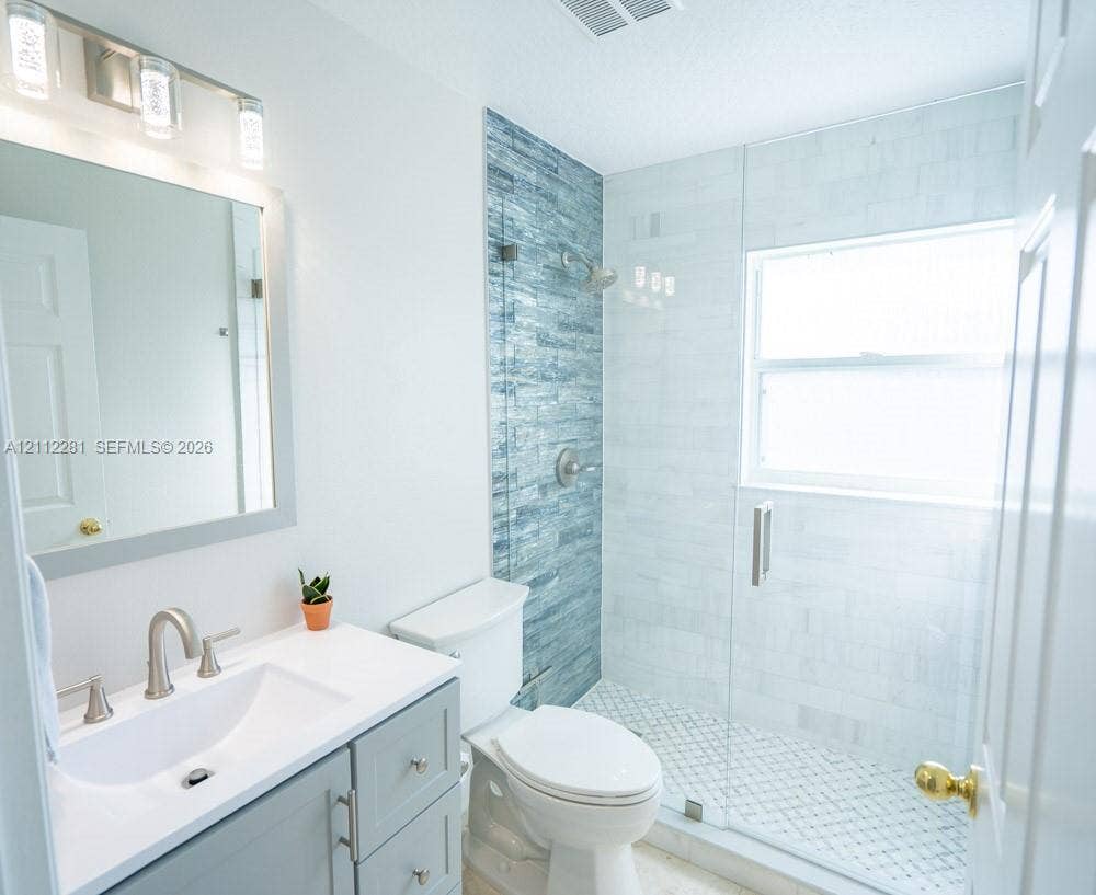 2461 Winfield, Kissimmee, FL 34743 Bathroom featuring a vanity with a white countertop and rectangular undermount sink, a walk-in shower with glass enclosure, textured blue tile accent wall, and three-light brushed-nickel fixture above the mirror