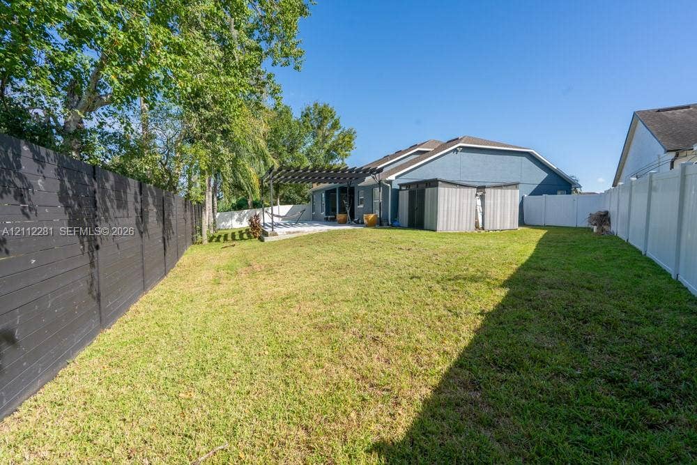 2461 Winfield, Kissimmee, FL 34743 Fenced backyard featuring a manicured lawn, wooden pergola, and mature trees