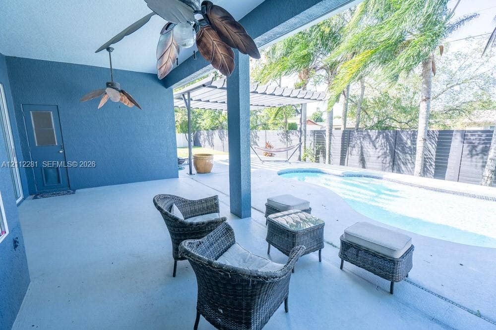 2461 Winfield, Kissimmee, FL 34743 Covered patio featuring two ceiling fans, in-ground swimming pool, horizontal slat privacy fencing, and a pergola-covered patio area
