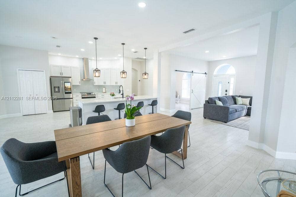 2461 Winfield, Kissimmee, FL 34743 Open-concept space featuring light wood-finish flooring, a kitchen island with stone-style countertops, shaker-style cabinetry, recessed lighting, and a barn-style sliding door
