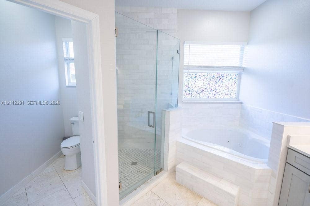 2461 Winfield, Kissimmee, FL 34743 Walk-in glass-enclosed shower featuring stone-tile surround, oversized soaking tub with tile deck, light-finish tile flooring, and integrated commode area