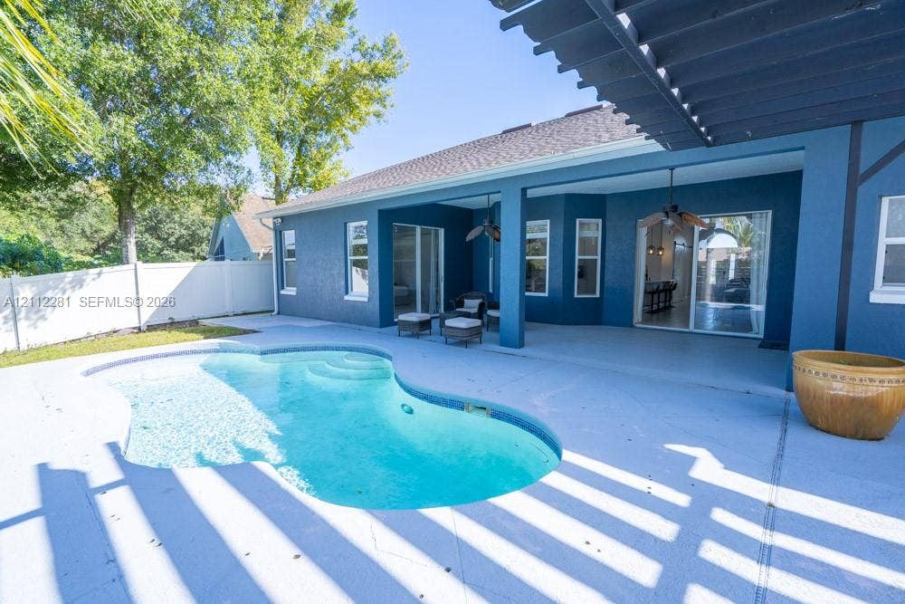 2461 Winfield, Kissimmee, FL 34743 Covered rear patio featuring a pergola, concrete decking, and an inground swimming pool with integrated steps, enclosed by privacy fencing