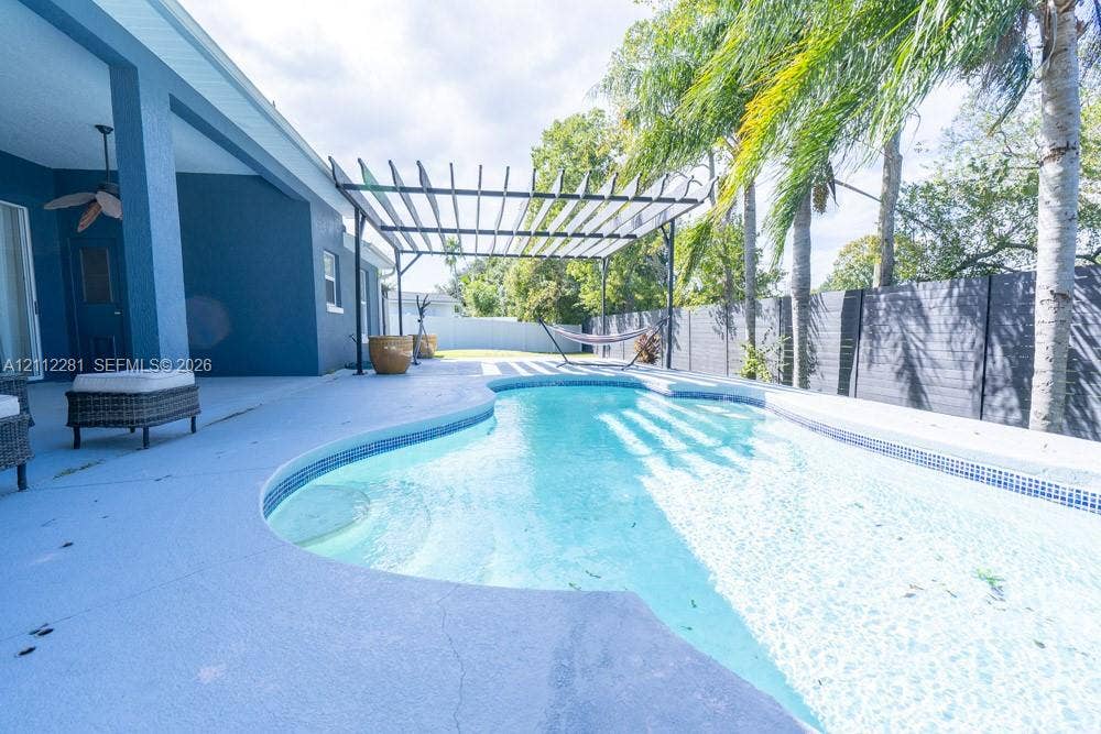 2461 Winfield, Kissimmee, FL 34743 Outdoor living space featuring an in-ground swimming pool, a metal pergola, a covered patio with a ceiling fan, and privacy fencing