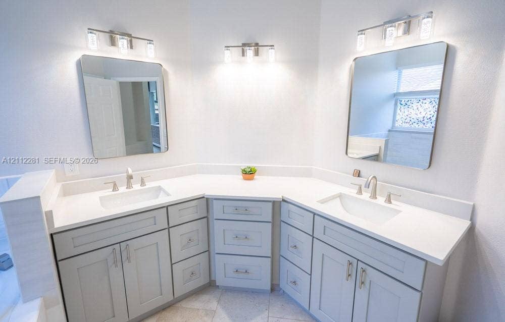 2461 Winfield, Kissimmee, FL 34743 Double vanity featuring grey shaker-style cabinetry, white solid-surface countertops, integrated rectangular sinks, brushed nickel faucets, and two three-light vanity fixtures