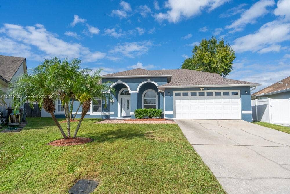 2461 Winfield, Kissimmee, FL 34743 Stucco exterior with arched architectural detailing, decorative entry columns, multi-pane garage door, and manicured landscaping