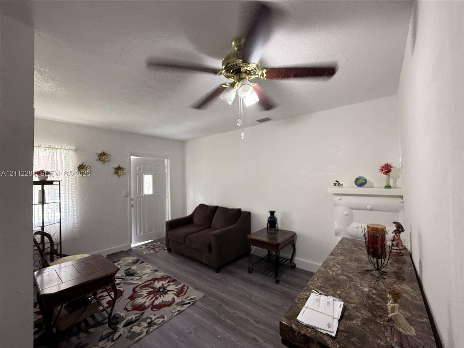 Wood-finish flooring, ceiling fan with integrated light fixture, built-in decorative wall mantle, and multi-pane entry door
