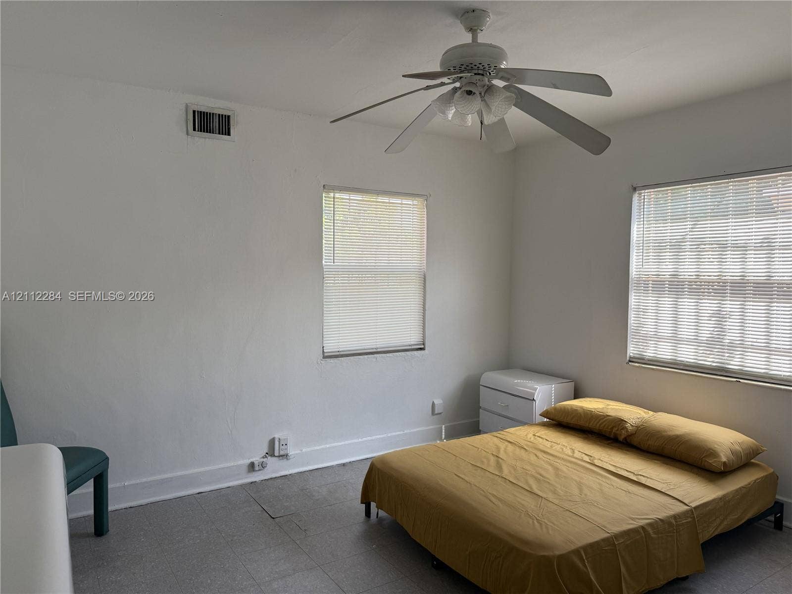 Neutral-toned room featuring a central ceiling fan with integrated lighting and two windows with horizontal blinds