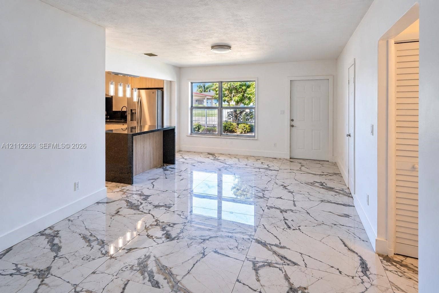 Polished stone-look flooring, kitchen island with dark solid-surface countertop, and recessed ceiling lighting
