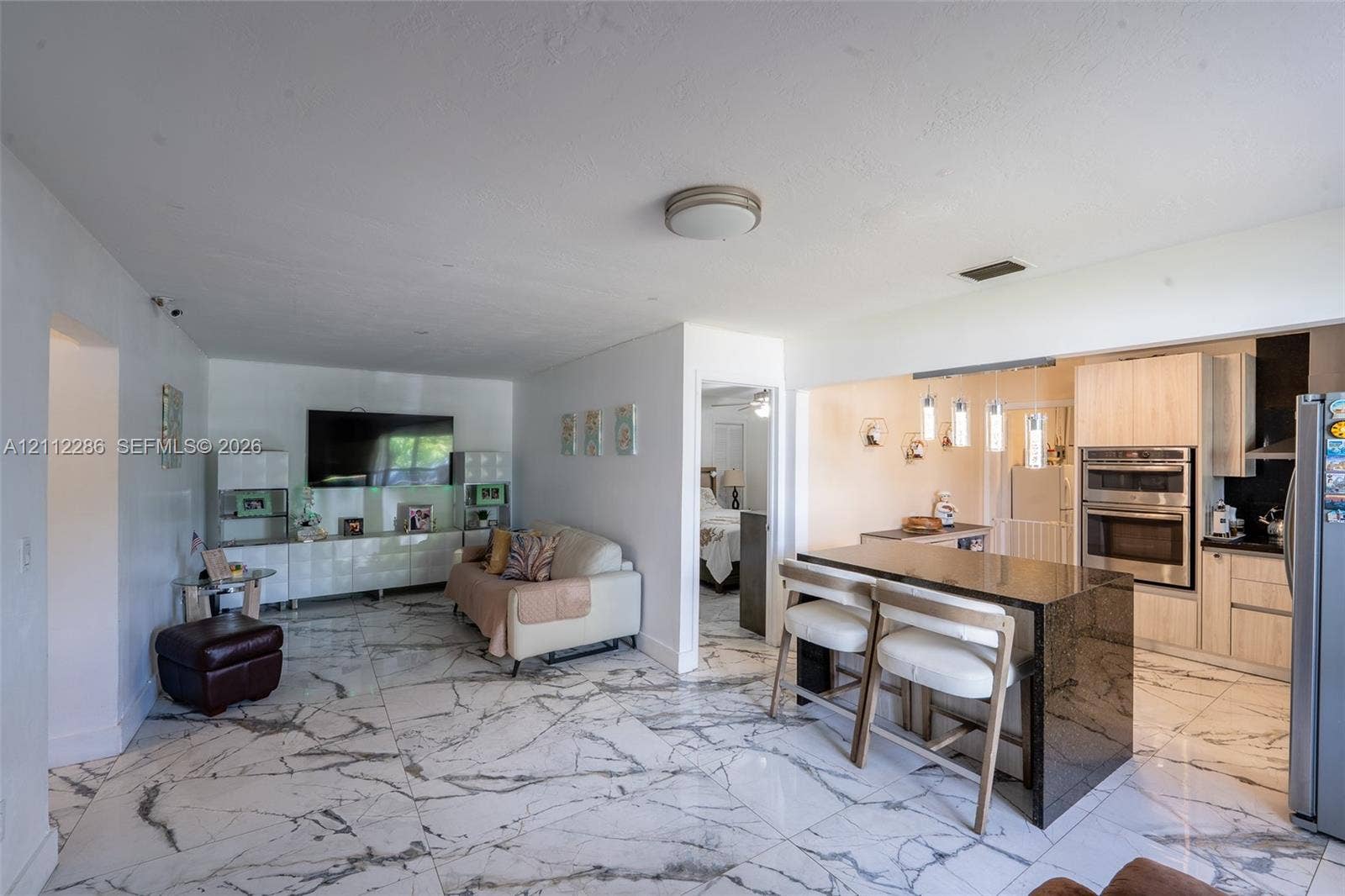 Large-format tile flooring, kitchen island with dark stone countertop, flat-panel cabinetry, and stainless steel double wall oven