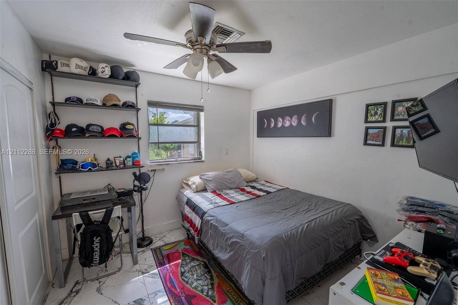 Room featuring white stone-finish tile flooring, ceiling fan with integrated lighting, and a single-pane window with horizontal blinds