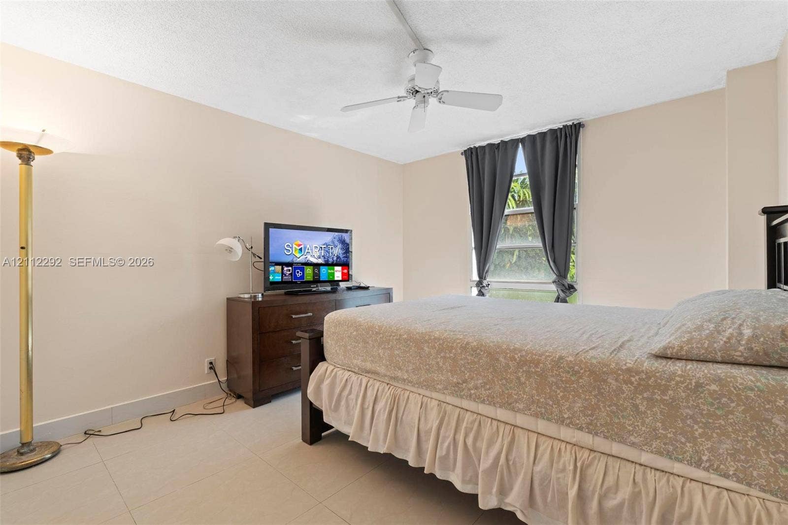 Room featuring light-toned neutral walls, polished tile flooring, and a ceiling-mounted fan