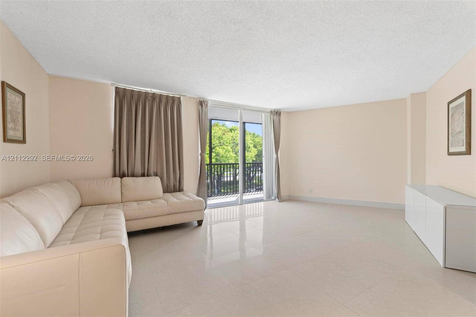 Living area featuring polished tile flooring, neutral wall tones, and glass sliding doors providing exterior access