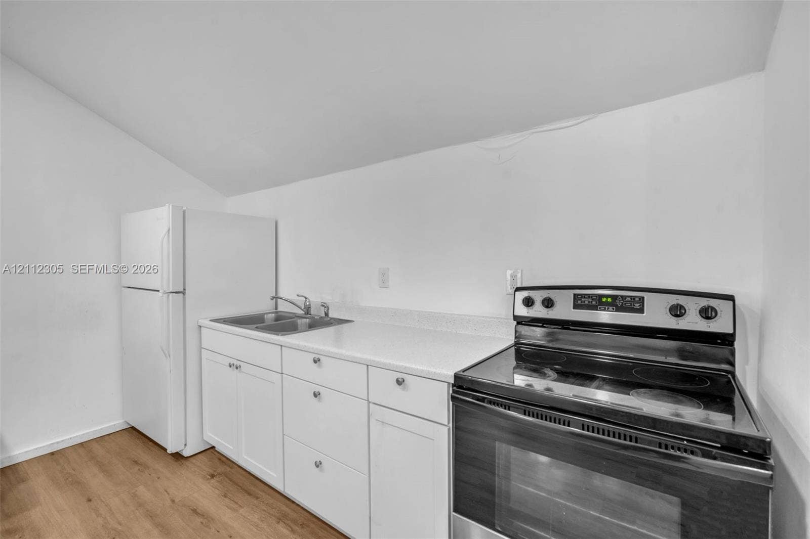 1008 N 18th Court, Hollywood, FL 33020 Kitchenette featuring white cabinetry, solid-surface countertops, a stainless steel dual-basin sink, a freestanding electric range, and wood-finish flooring