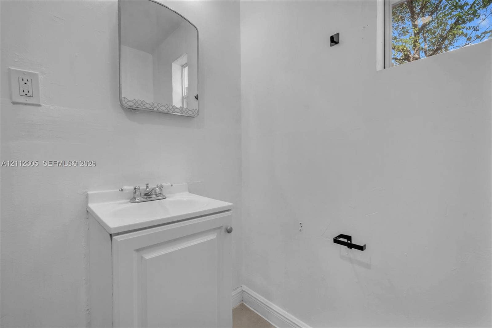 1008 N 18th Court, Hollywood, FL 33020 White vanity cabinet with an integrated top, chrome finish faucet, wall-mounted rectangular mirror, and matte black hardware fixtures