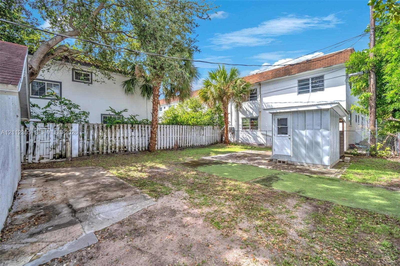 1008 N 18th Court, Hollywood, FL 33020 Rear exterior featuring a detached structure, concrete patio, artificial turf area, and full-perimeter wood fencing