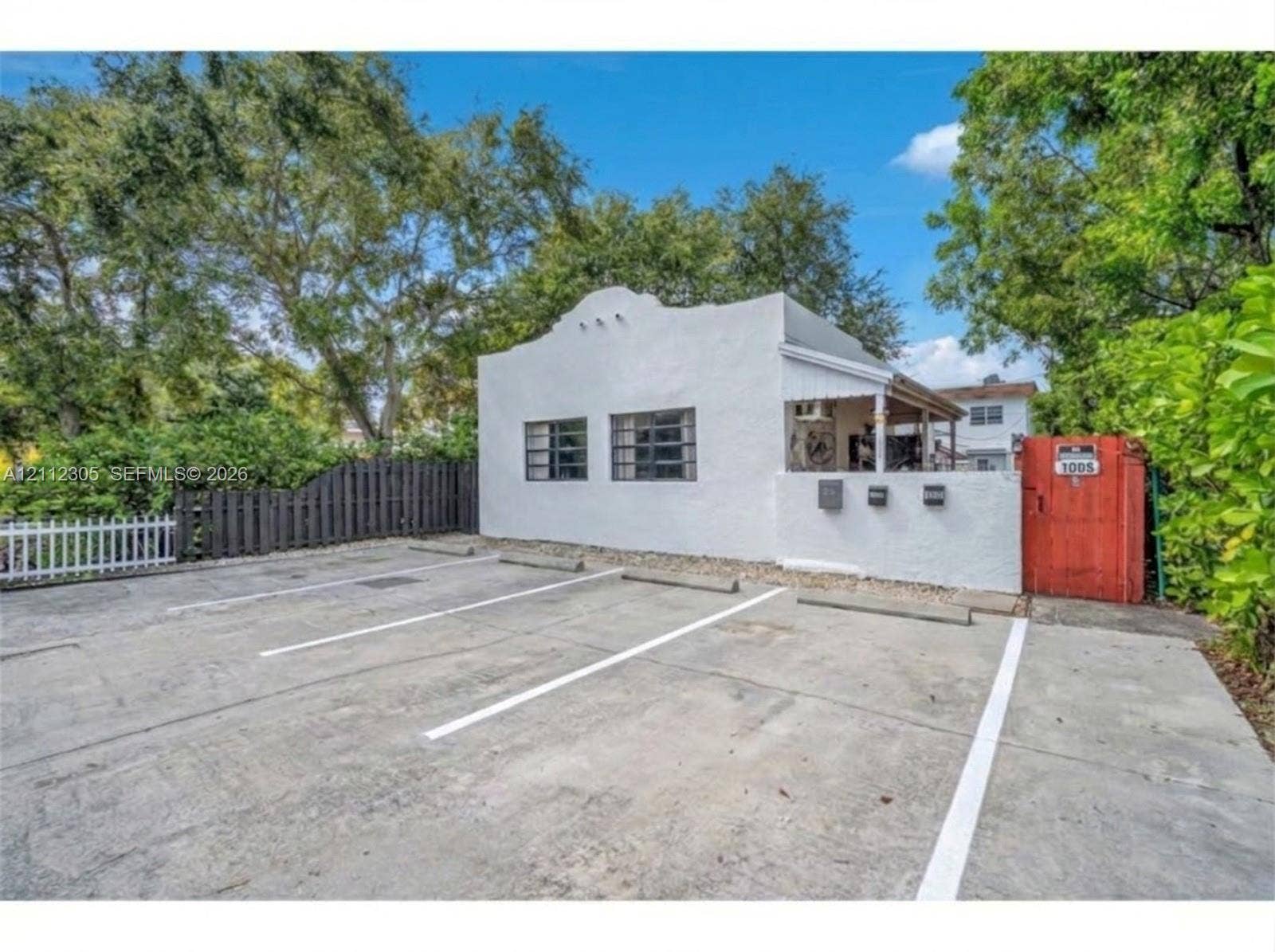 1008 N 18th Court, Hollywood, FL 33020 AI enhanced: house repainted a brighter white, fence stained, parking lot cleaned and striped for 4 spaces. Nothing structural changed. The unaltered original is the next photo.