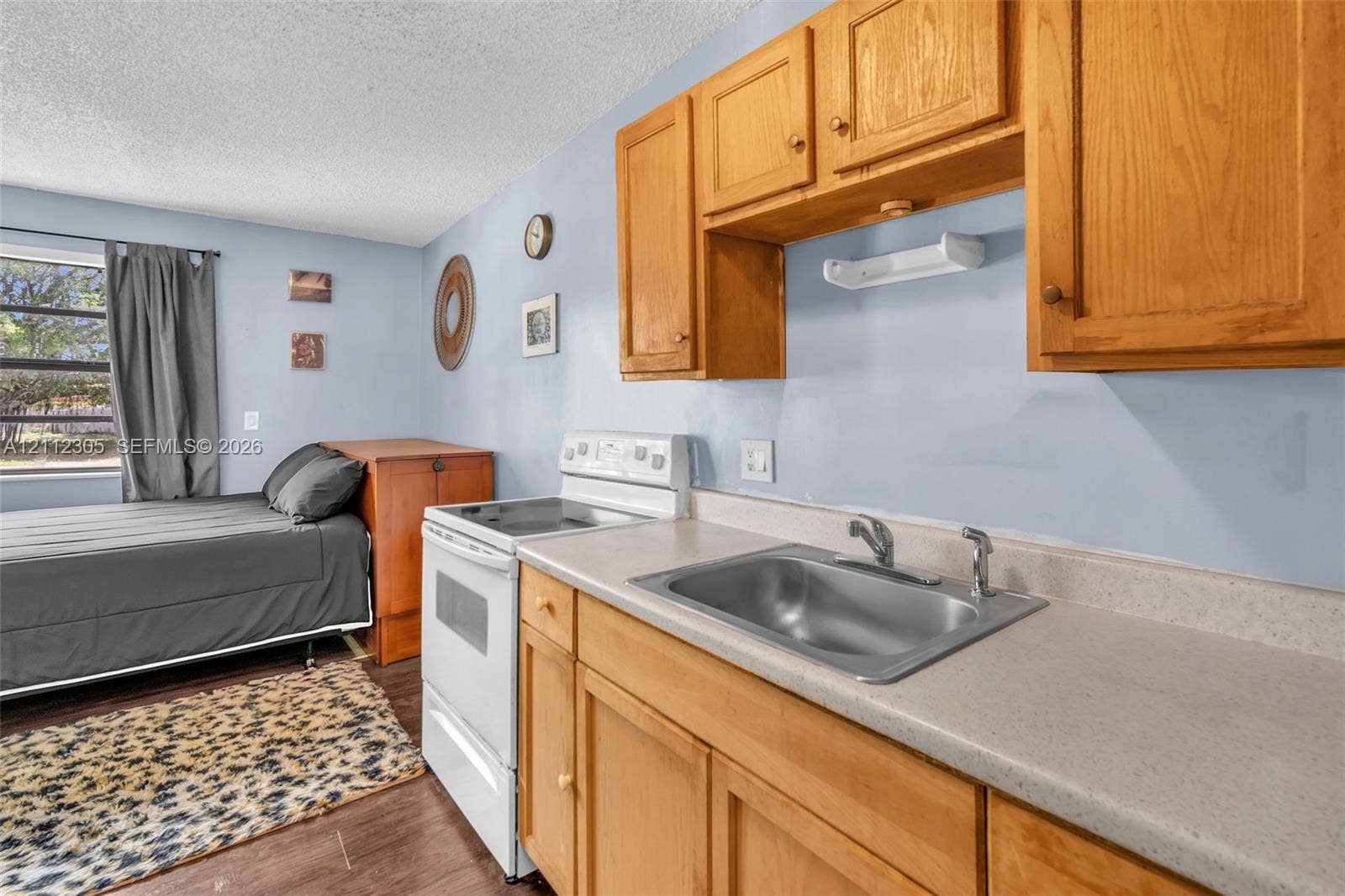 1008 N 18th Court, Hollywood, FL 33020 Kitchenette featuring wood-finish cabinetry, solid-surface countertops, a stainless steel sink with a dual-handle faucet, and an electric range