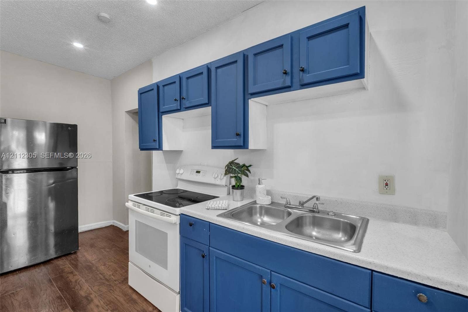 1008 N 18th Court, Hollywood, FL 33020 Kitchen featuring blue cabinetry, white countertops, double basin stainless steel sink, stainless steel refrigerator, and wood-finish flooring