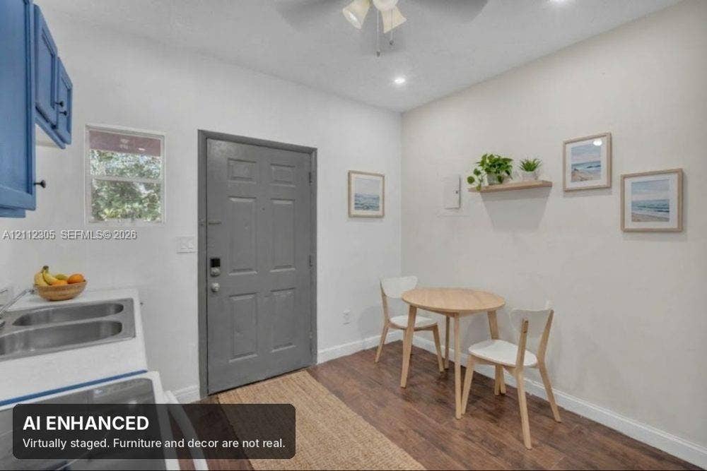 1008 N 18th Court, Hollywood, FL 33020 Covered entryway featuring a textured stucco exterior, a solid six-panel door, an exterior wall-mounted light fixture, and a masonry planter box