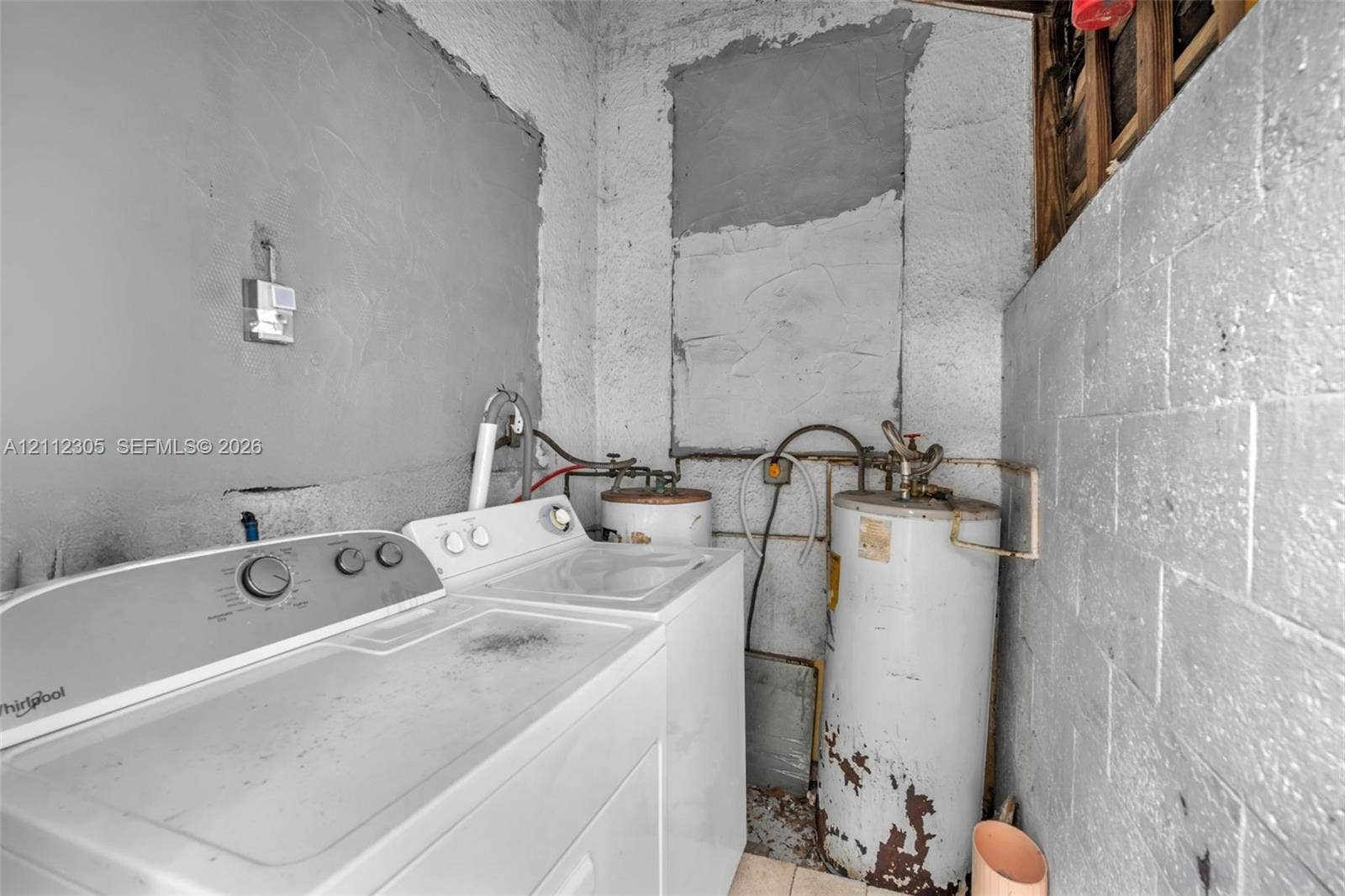 1008 N 18th Court, Hollywood, FL 33020 Utility area featuring exposed concrete block walls and a vertical water heater