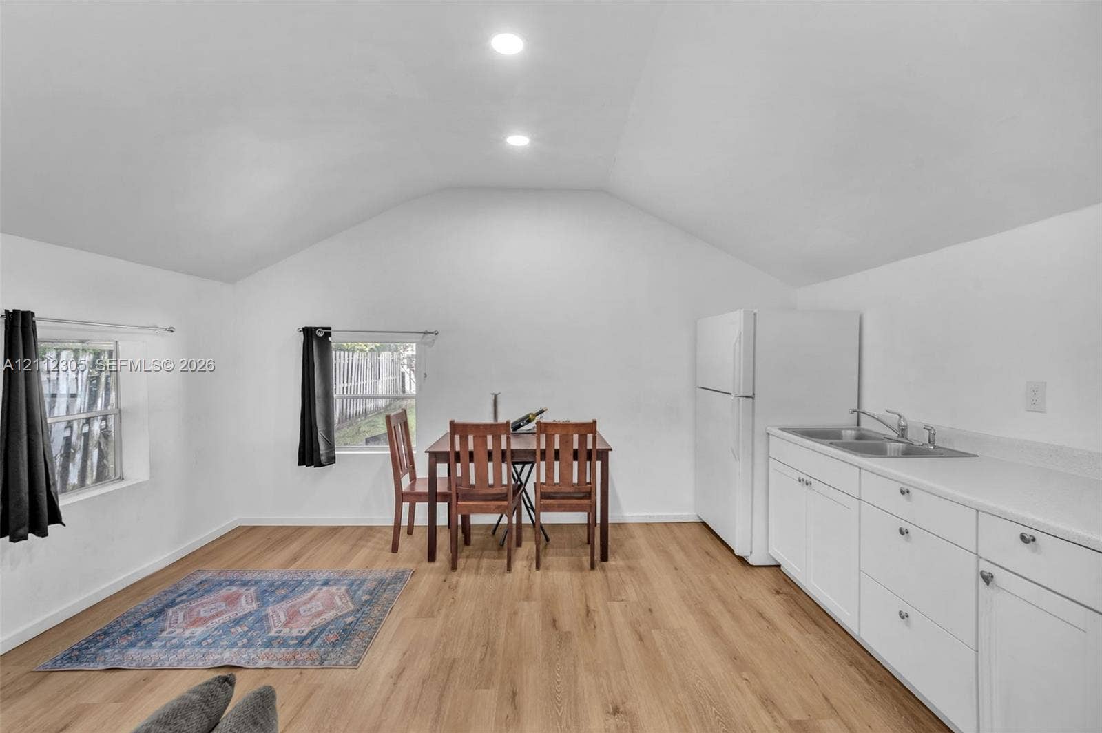 1008 N 18th Court, Hollywood, FL 33020 Stucco exterior featuring a mission-style parapet, dual-pane windows, dedicated asphalt parking spaces, and wood-slat privacy fencing