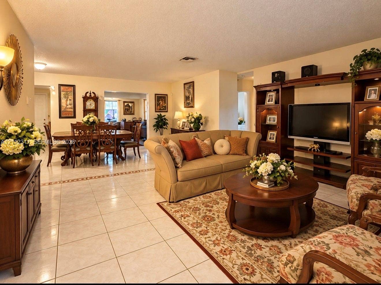390 NW 49th Avenue, Plantation, FL 33317 Open-concept living space featuring large-format ceramic tile flooring, built-in wooden shelving unit, and decorative tile inlay detail