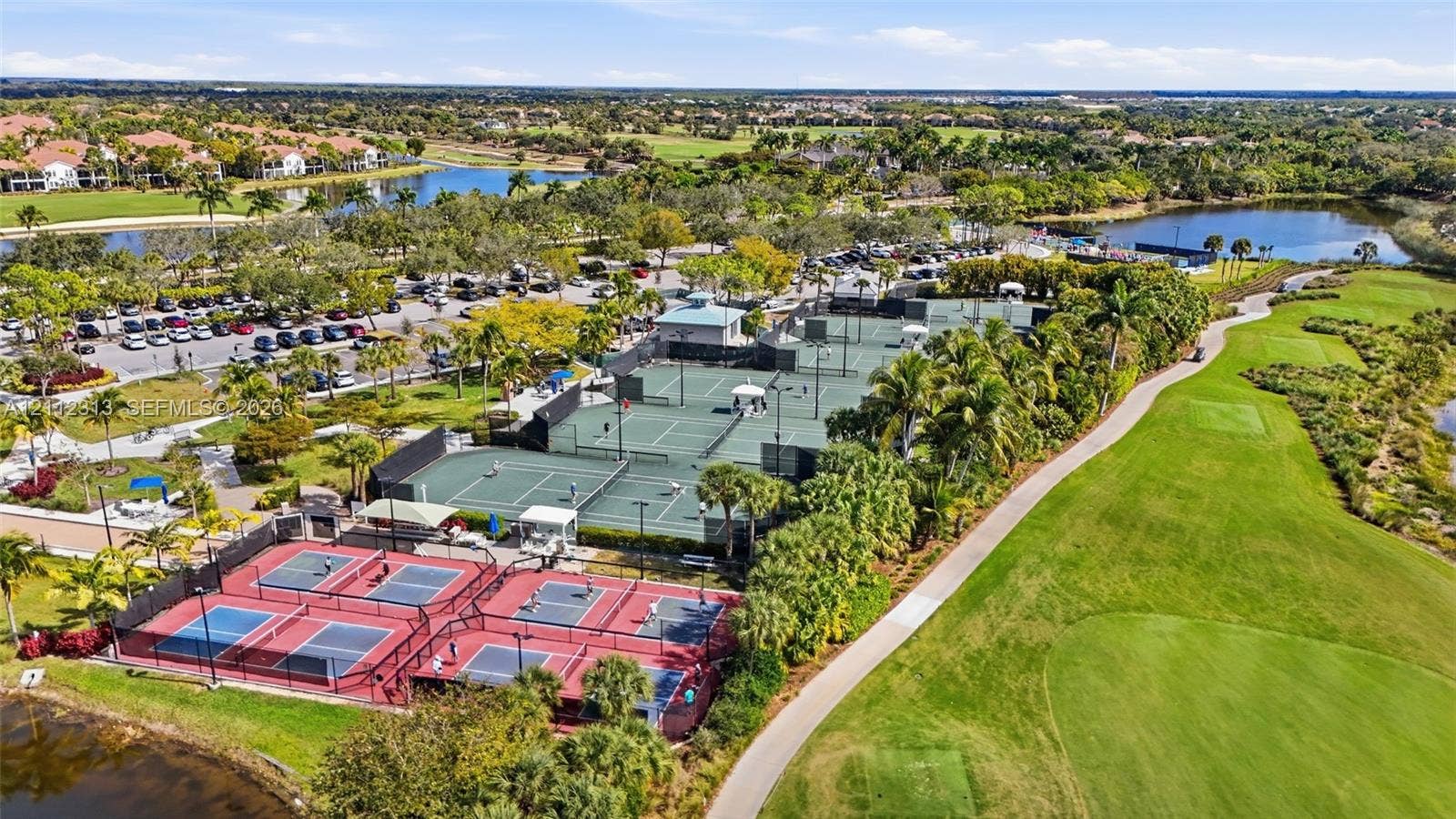 Aerial recreation area featuring multiple tennis courts, pickleball courts, manicured green space, and water features