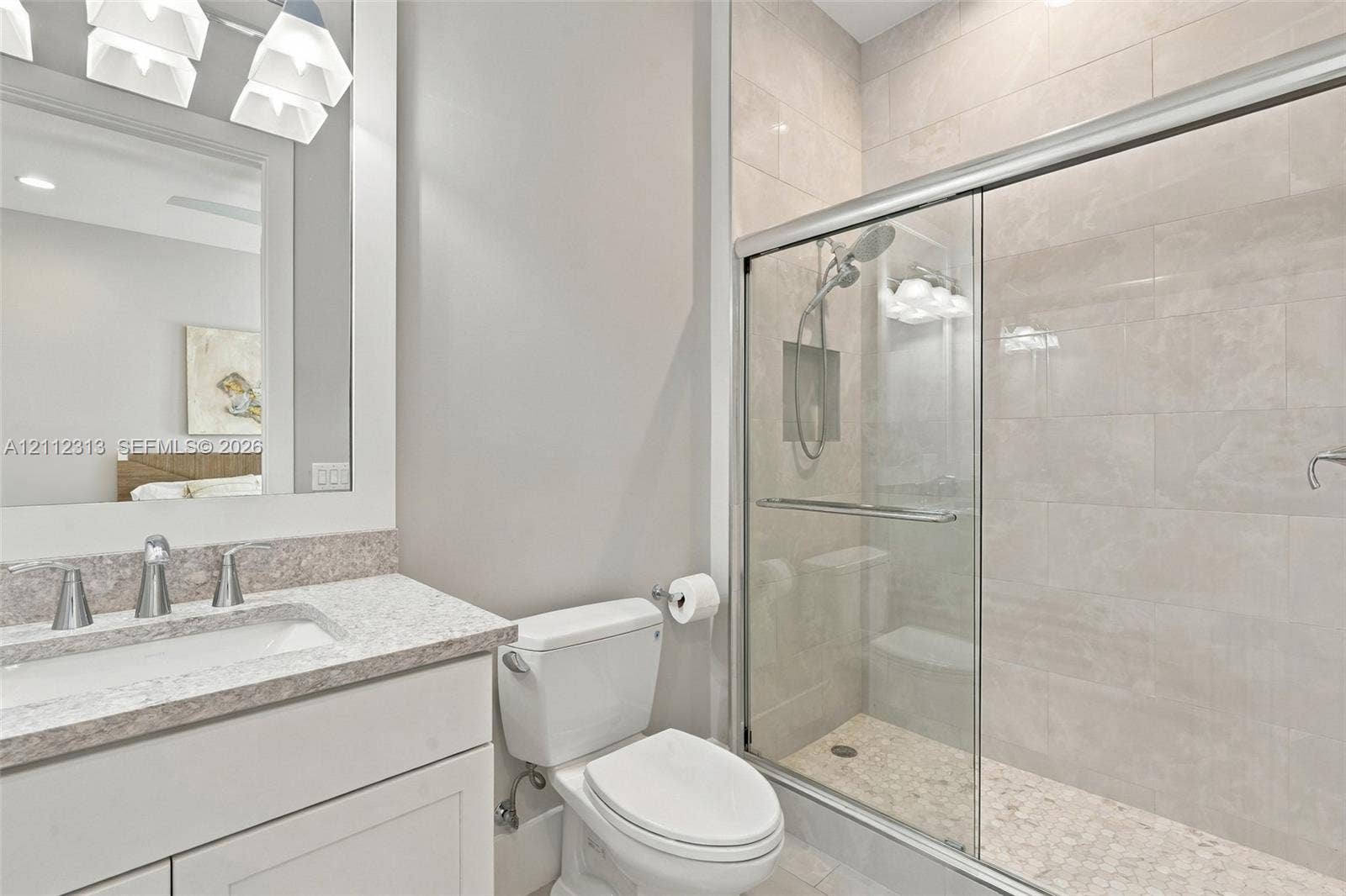 Bathroom featuring a vanity with a light-toned countertop, a frameless glass-enclosed shower with tiled walls and a built-in recessed niche, and polished chrome fixtures
