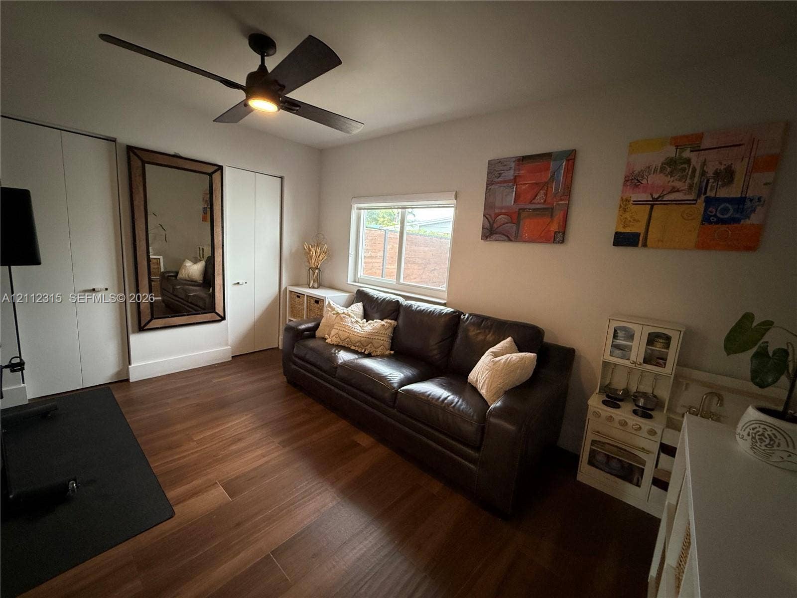 Wood-finish flooring, ceiling fan with integrated light, and dual-closet storage with white doors