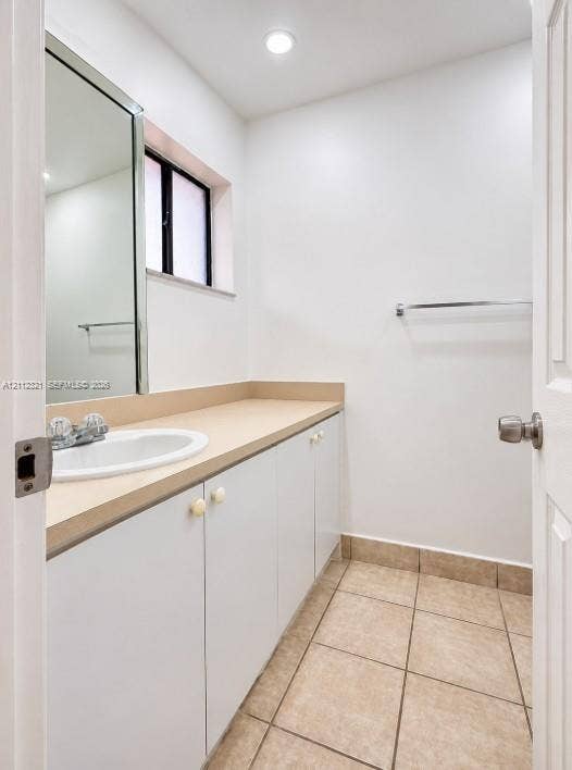 Bathroom featuring a white vanity with a neutral solid-surface countertop, an integrated drop-in sink, recessed lighting, and tile flooring