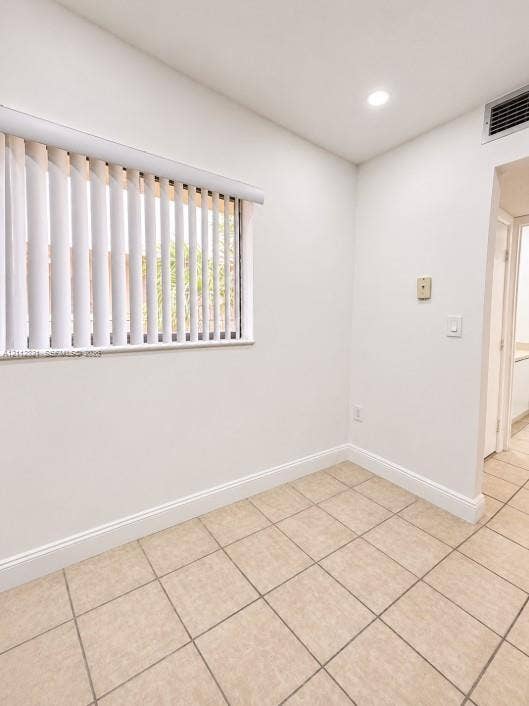 Neutral-toned ceramic tile flooring, recessed ceiling lighting, and vertical window blinds