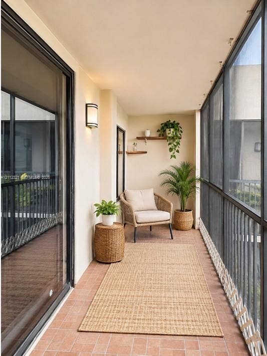Covered balcony featuring terracotta-tile flooring, metal screen enclosure, wall-mounted exterior light fixture, and two built-in floating shelves