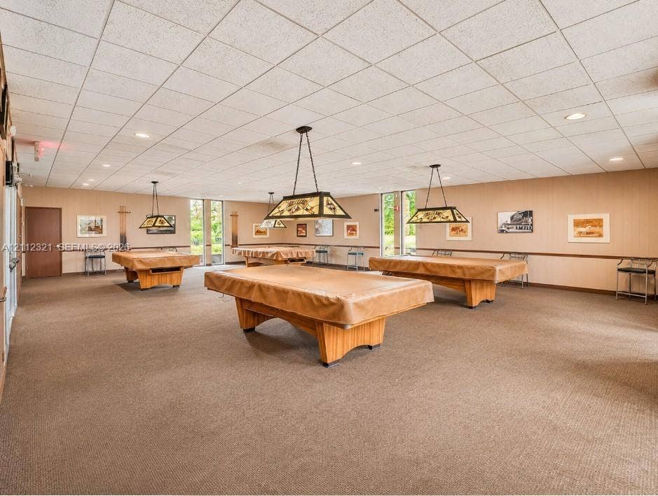 Spacious recreation area featuring a drop ceiling, wall-to-wall carpeting, recessed lighting, and built-in drop-pendant lighting fixtures