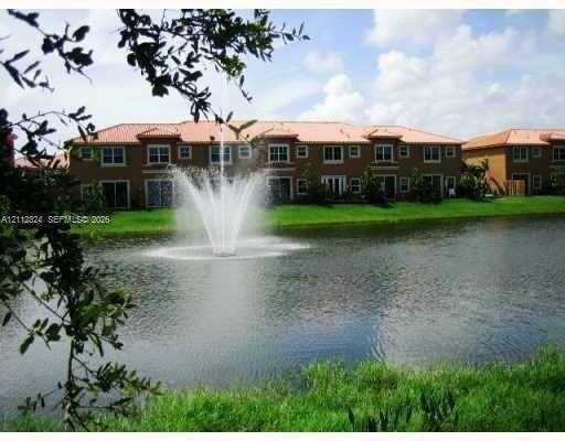 Waterfront building exterior featuring a tiled roof, multi-story masonry construction, and a central water fountain