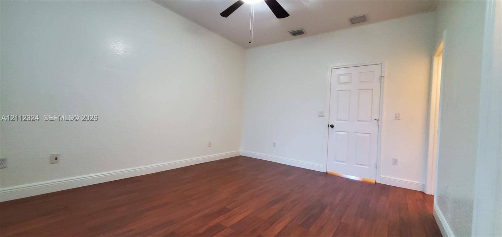 Vaulted ceiling featuring a central multi-blade ceiling fan and wood-finish flooring
