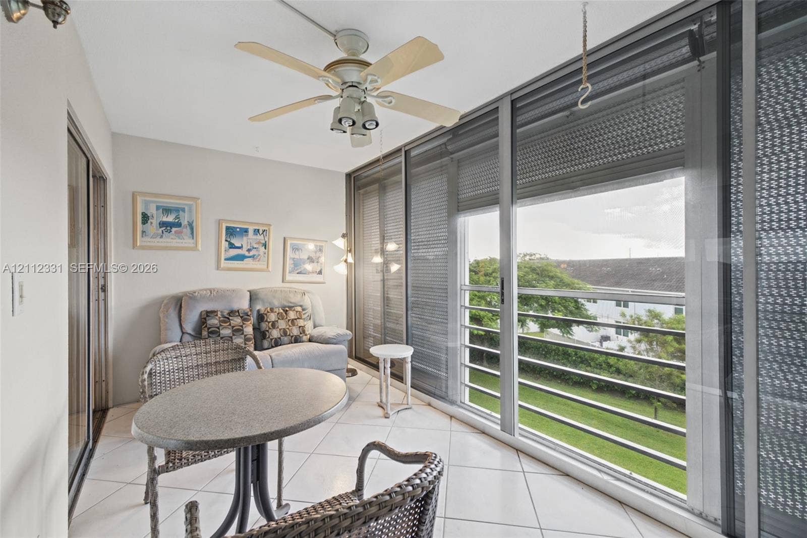 4025 Upminster K, #4025, Deerfield Beach, FL 33442 Enclosed balcony featuring large-format ceramic tile flooring, a white ceiling fan with integrated lighting, and expansive floor-to-ceiling sliding glass doors with horizontal blinds