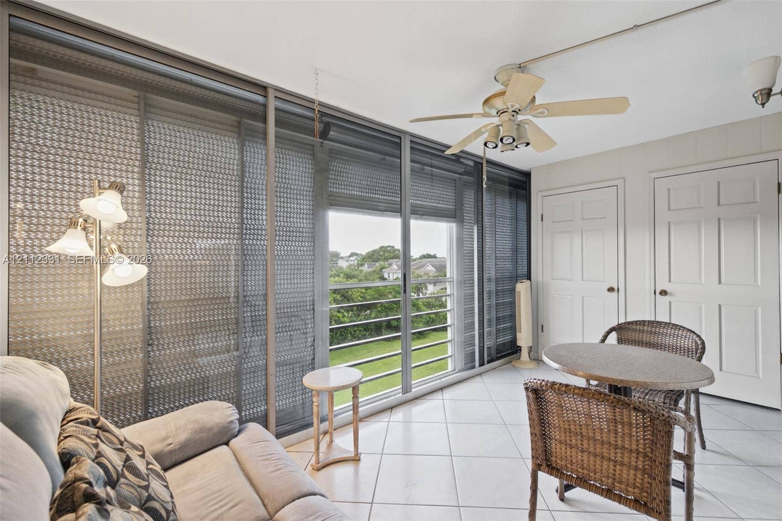 4025 Upminster K, #4025, Deerfield Beach, FL 33442 Enclosed sunroom featuring light-colored ceramic tile flooring, floor-to-ceiling sliding glass doors, a ceiling fan with integrated lighting, and two interior six-panel doors
