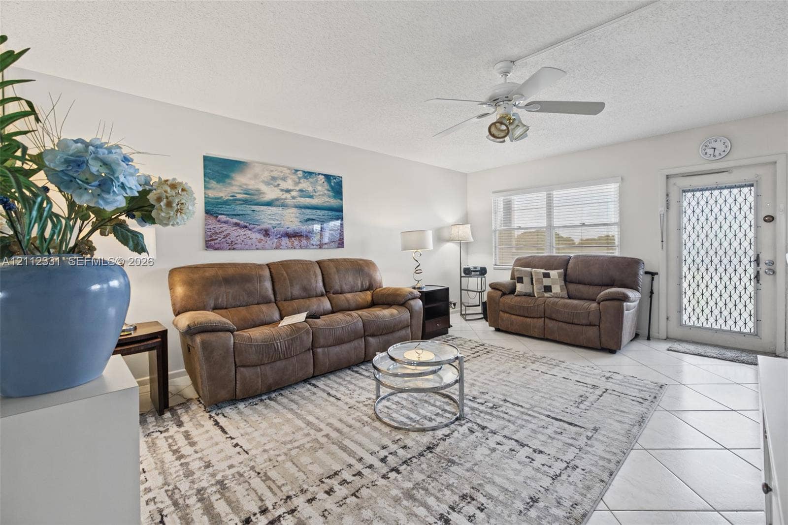 4025 Upminster K, #4025, Deerfield Beach, FL 33442 Living area featuring neutral-toned tile flooring, a multi-blade ceiling fan with integrated lighting, and a security-screen entry door