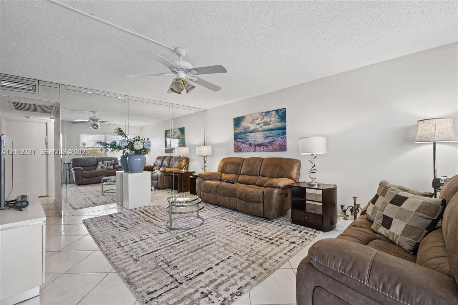 4025 Upminster K, #4025, Deerfield Beach, FL 33442 Living area featuring neutral tile flooring, mirrored wall paneling, and a ceiling-mounted light fixture with fan