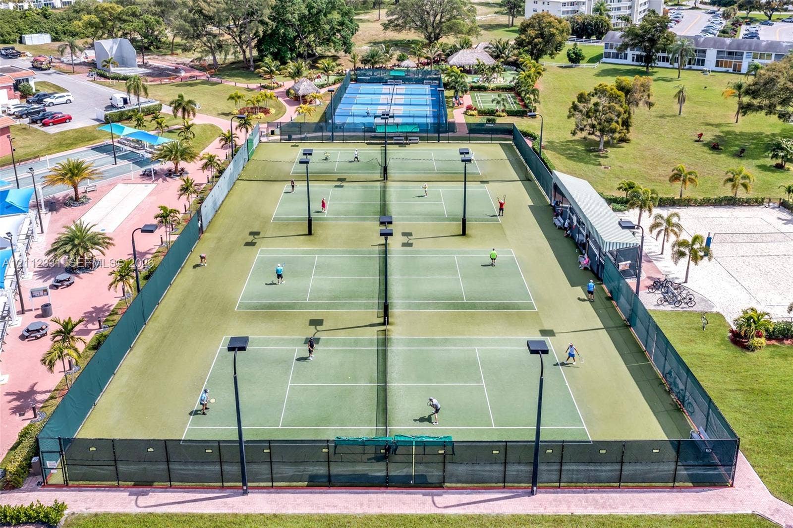 4025 Upminster K, #4025, Deerfield Beach, FL 33442 Multi-court tennis facility featuring perimeter chain-link fencing, court lighting, and paved pathways
