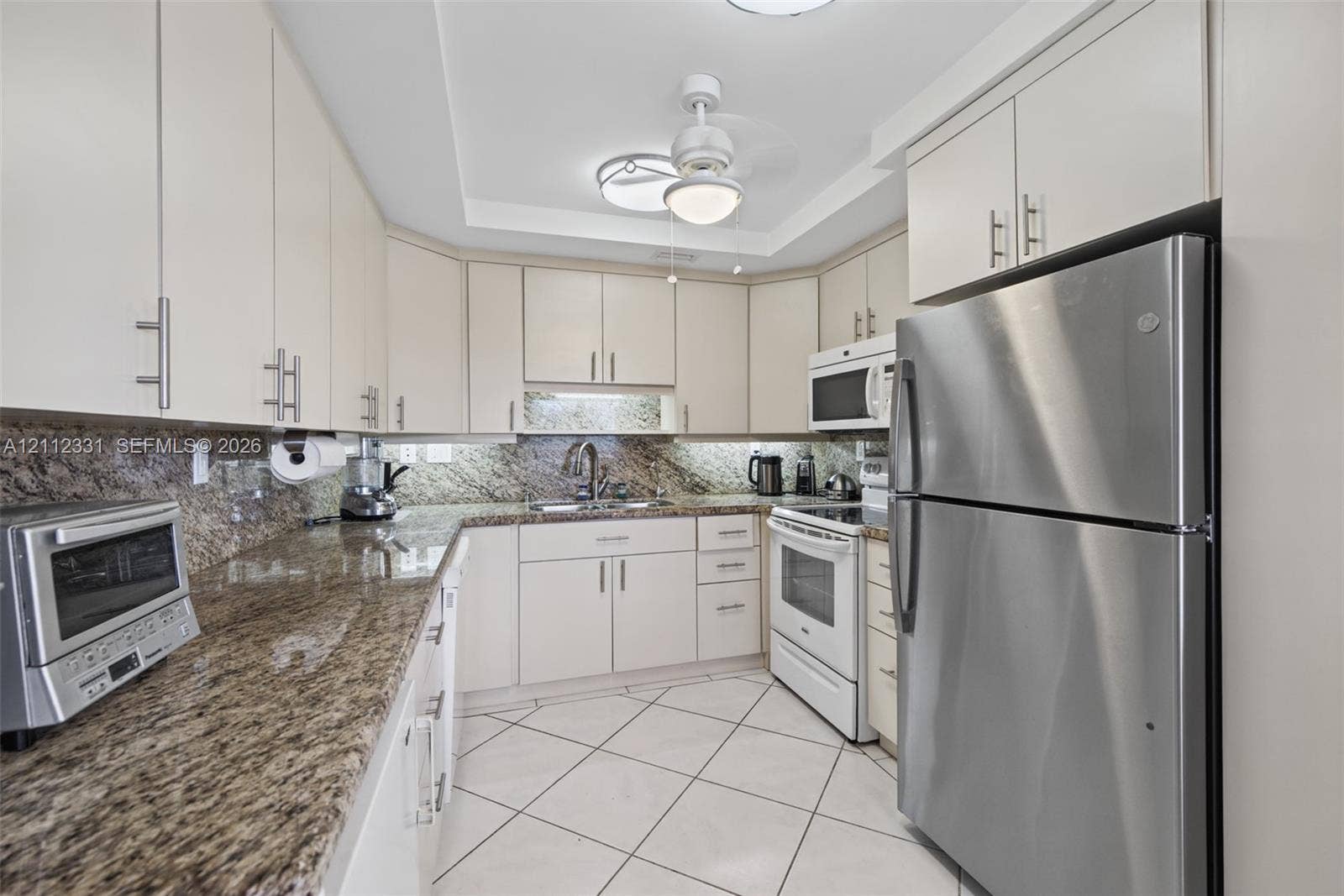 4025 Upminster K, #4025, Deerfield Beach, FL 33442 Kitchen featuring white cabinetry, stone-patterned countertops, stainless steel appliances, and tiled flooring