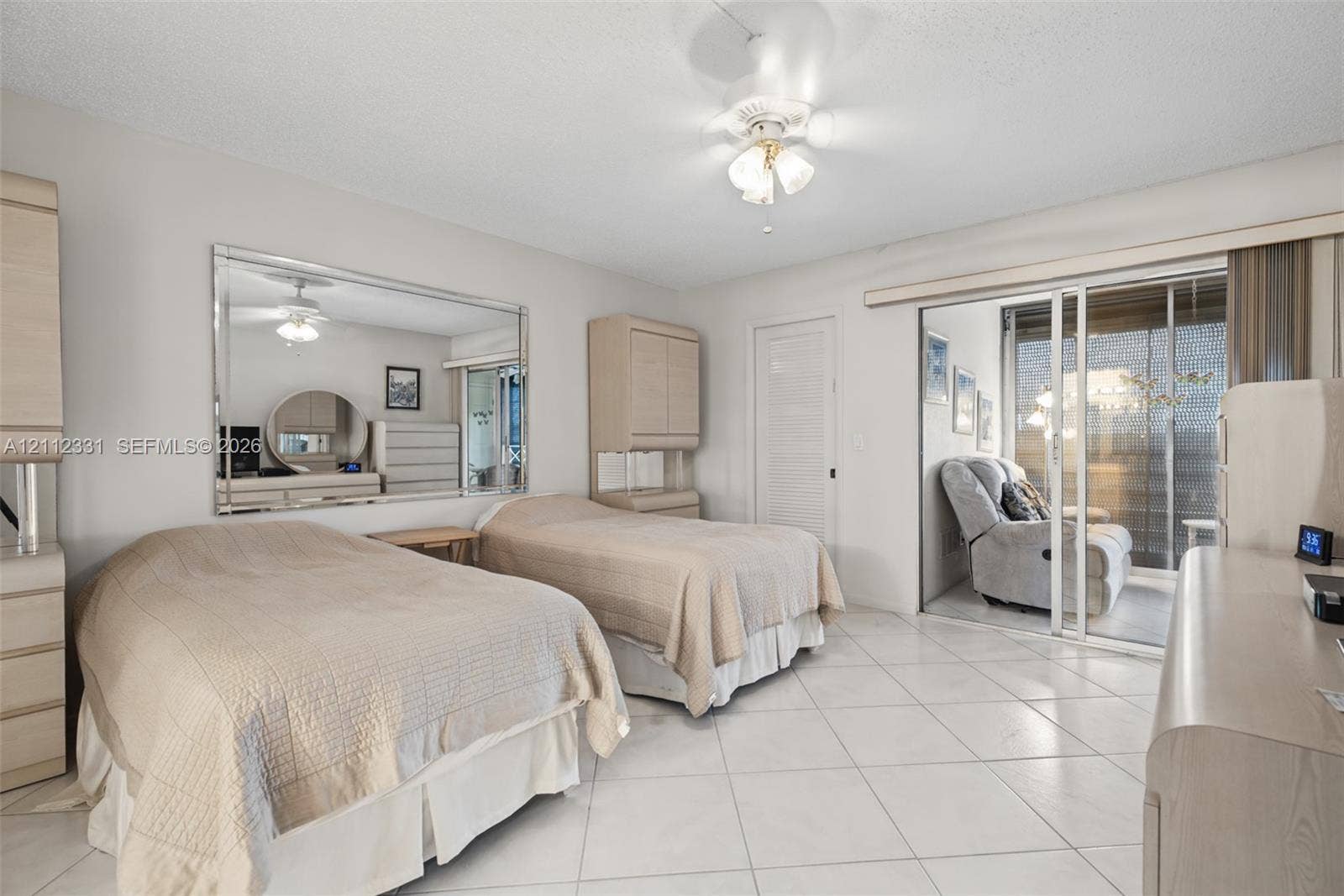 4025 Upminster K, #4025, Deerfield Beach, FL 33442 Tile flooring, large wall-mounted mirror, ceiling fan with integrated lighting, and sliding glass door with exterior balcony access