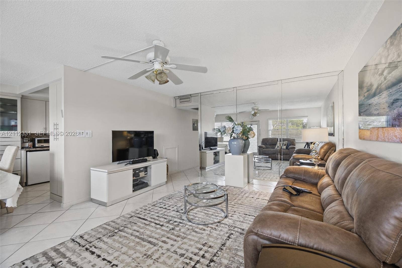 4025 Upminster K, #4025, Deerfield Beach, FL 33442 Open-concept interior featuring large-format diagonal tile flooring, a ceiling fan with integrated lighting, and a full-wall mirrored accent