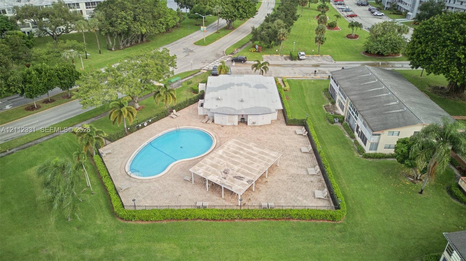 4025 Upminster K, #4025, Deerfield Beach, FL 33442 Outdoor swimming pool featuring a paved patio area, shaded pergola, perimeter hedging, and mature landscaping