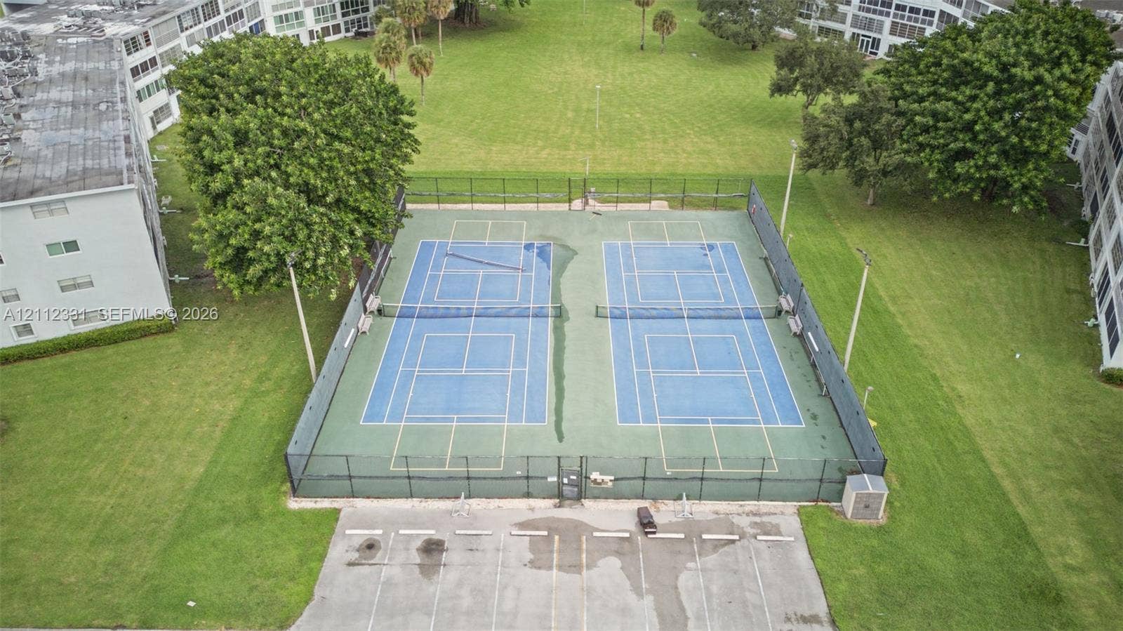 4025 Upminster K, #4025, Deerfield Beach, FL 33442 Dual tennis courts featuring hard-court surfaces, perimeter fencing, and integrated lighting