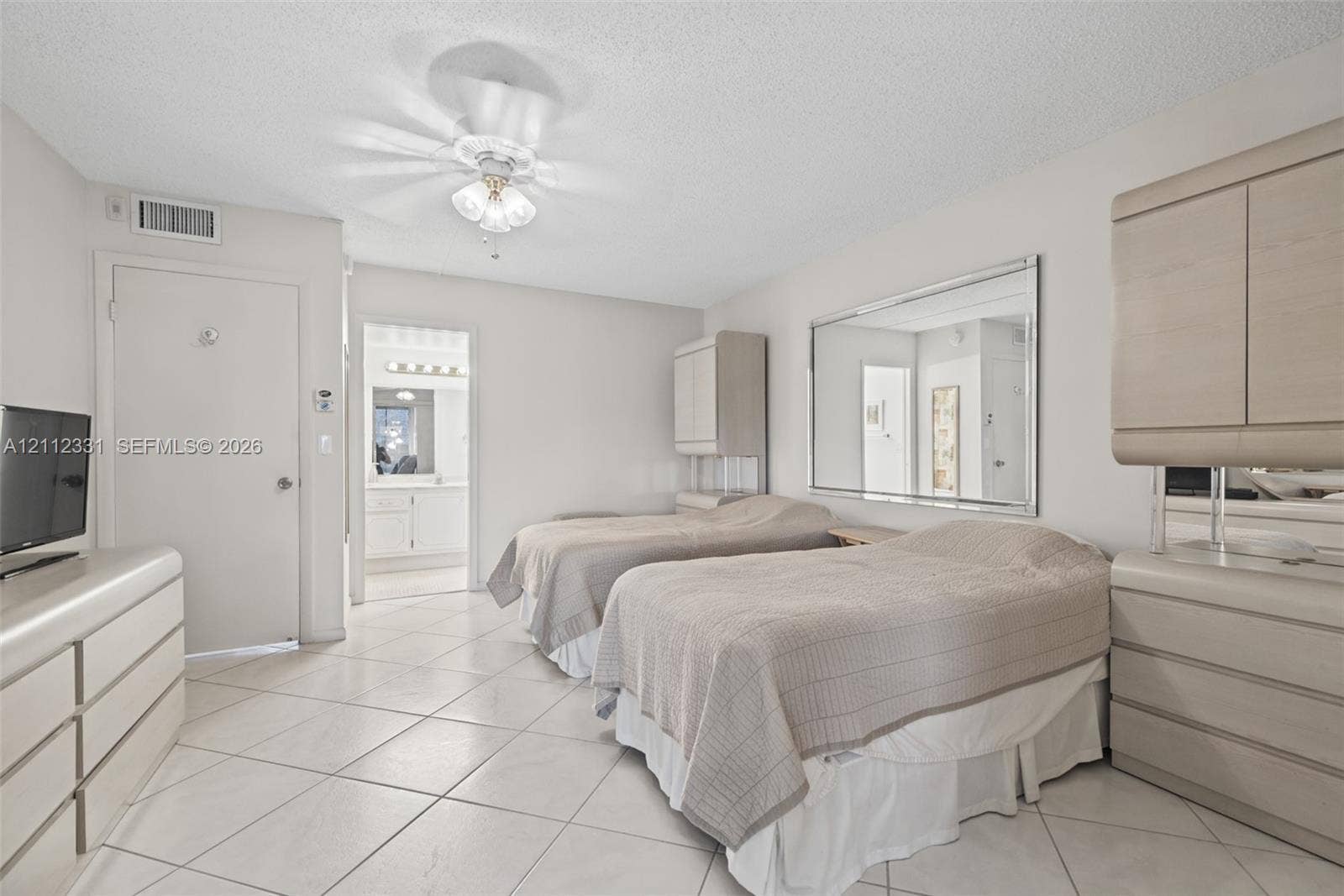 4025 Upminster K, #4025, Deerfield Beach, FL 33442 Neutral-toned space featuring large-format diagonal tile flooring, custom built-in light-wood cabinetry, a wall-mounted glass mirror, and a central ceiling fan with integrated lighting