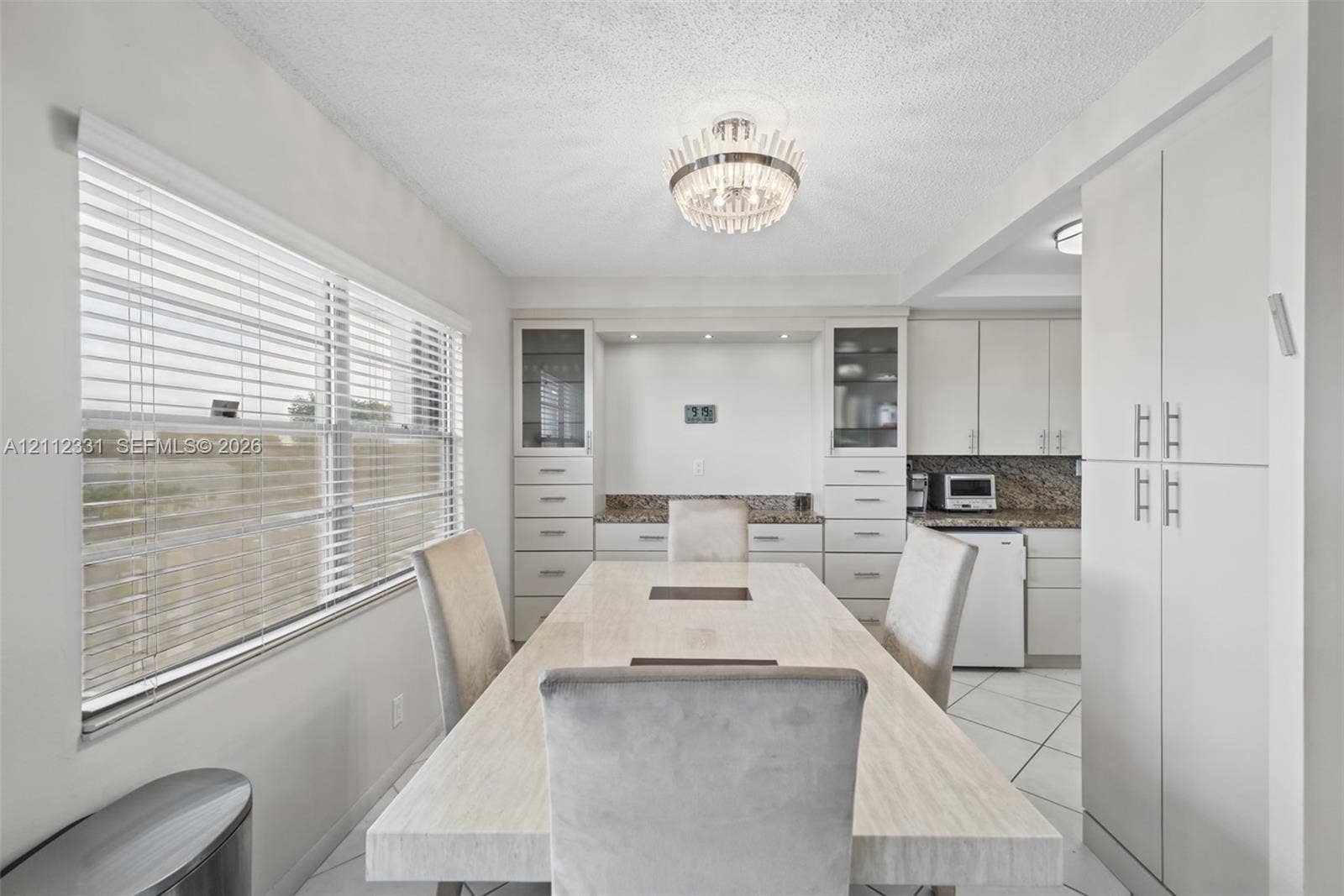 4025 Upminster K, #4025, Deerfield Beach, FL 33442 Built-in cabinetry with integrated shelving and drawers, stone-finish countertops, tile flooring, large horizontal window with blinds, and decorative chandelier lighting