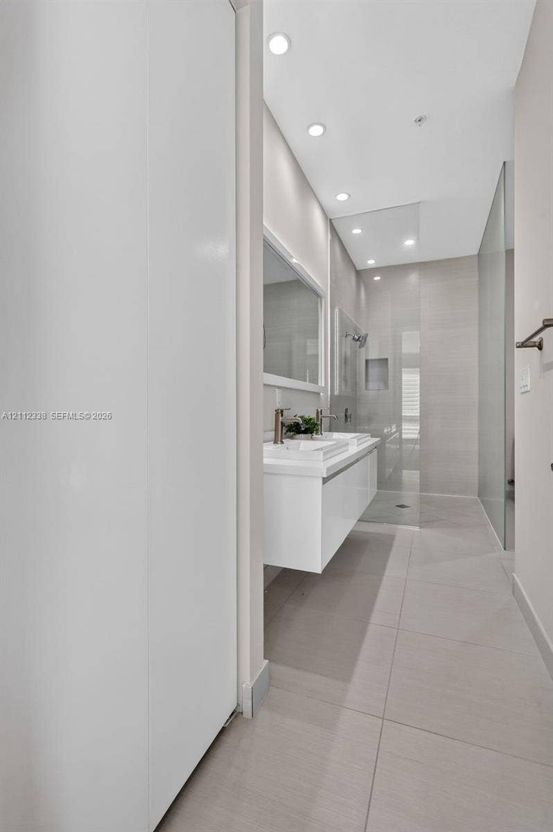10305 NW 63rd Terrace, #102, Doral, FL 33178 Floating white vanity with dual vessel sinks, recessed lighting, and a walk-in shower featuring a glass enclosure and recessed shelving